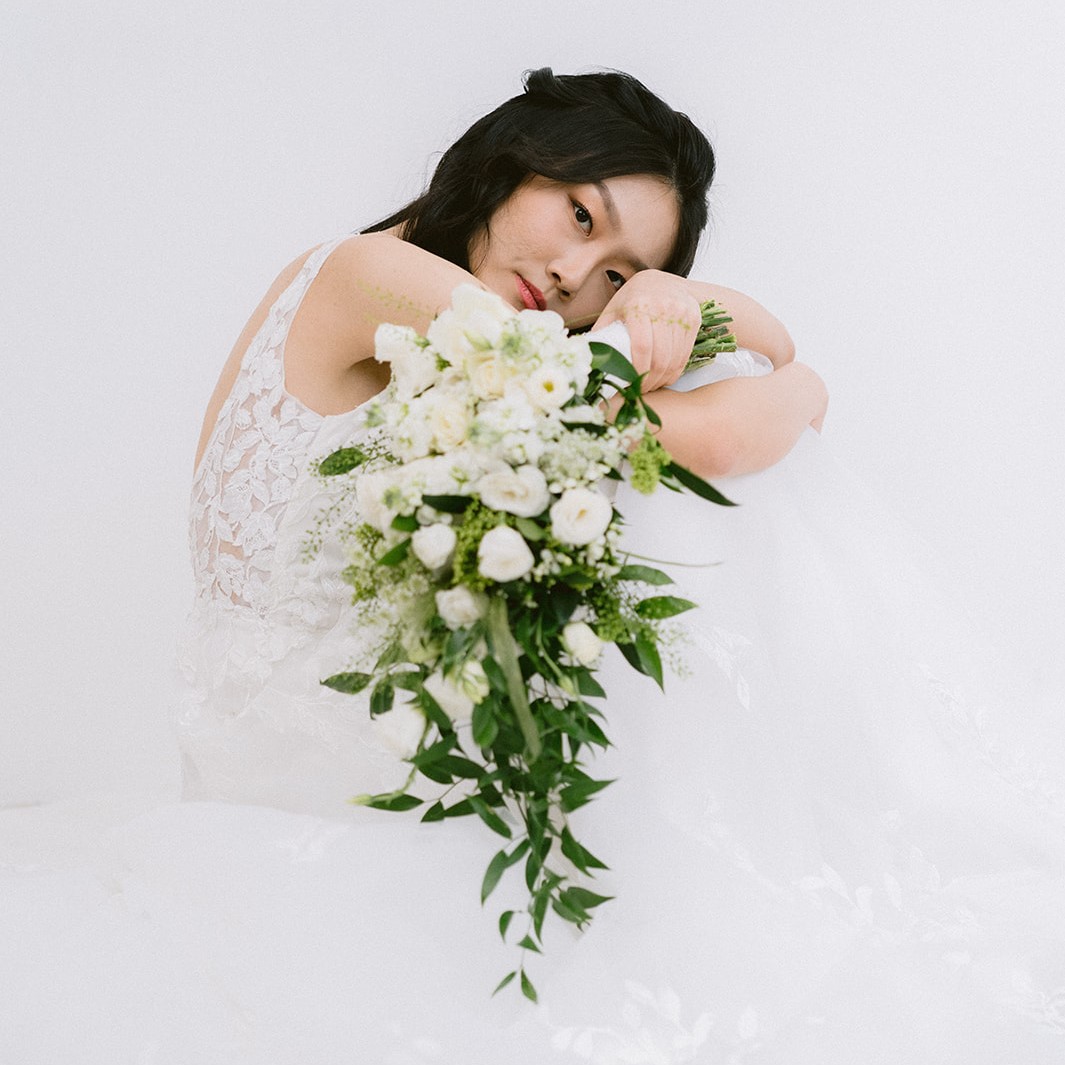 A  women is holding a Cascading Lisianthus Bridal Bouquet